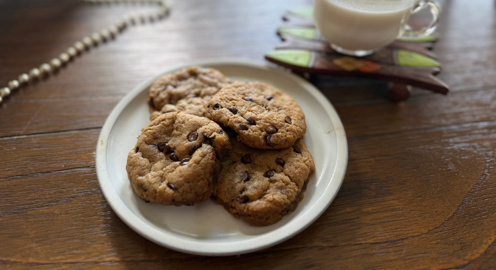 Image of vegan chocolate chip cookies served on a plate with a warm drink, a dairy-free baked dessert made with chocolate chips.